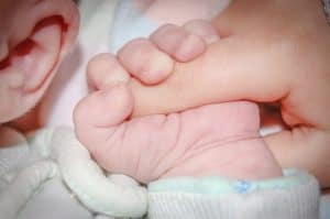 תינוק בן יומו נאחז האצבע של בוגר